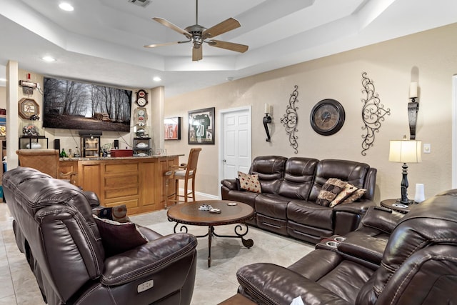 tiled living room featuring a tray ceiling and ceiling fan