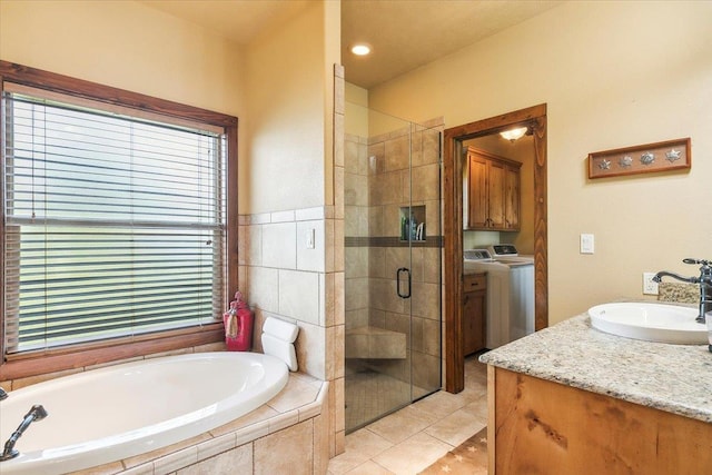 bathroom with plus walk in shower, washer and clothes dryer, vanity, and tile patterned flooring