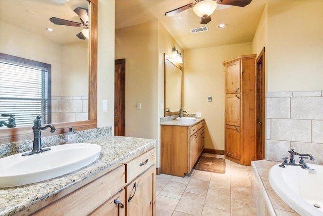 bathroom with tile patterned floors, tiled tub, and vanity