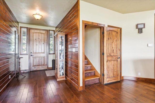 entryway featuring wood walls and dark wood-type flooring