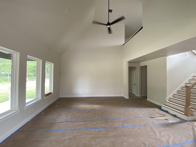 unfurnished living room with ceiling fan and a towering ceiling