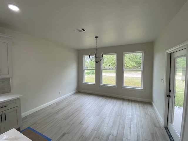 unfurnished dining area with light wood-type flooring and a notable chandelier