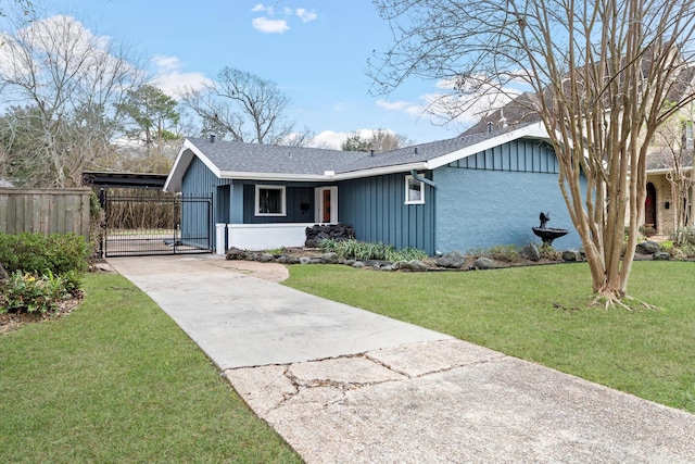 view of front of property featuring board and batten siding, a gate, fence, driveway, and a front lawn