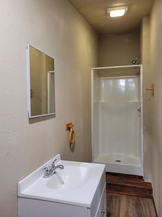 bathroom with hardwood / wood-style floors, vanity, and walk in shower