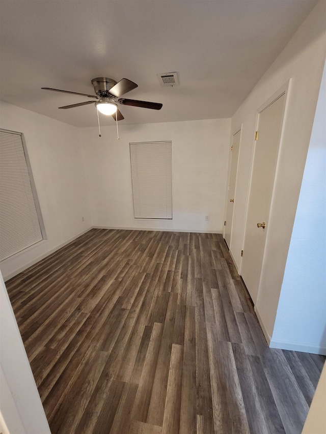 empty room with ceiling fan and dark wood-type flooring