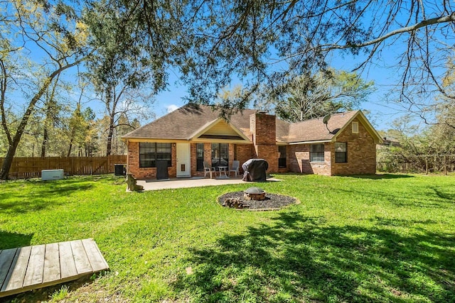 back of house with a lawn, a patio, a fire pit, brick siding, and fence private yard