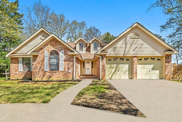 traditional-style house featuring driveway, fence, an attached garage, a front yard, and brick siding