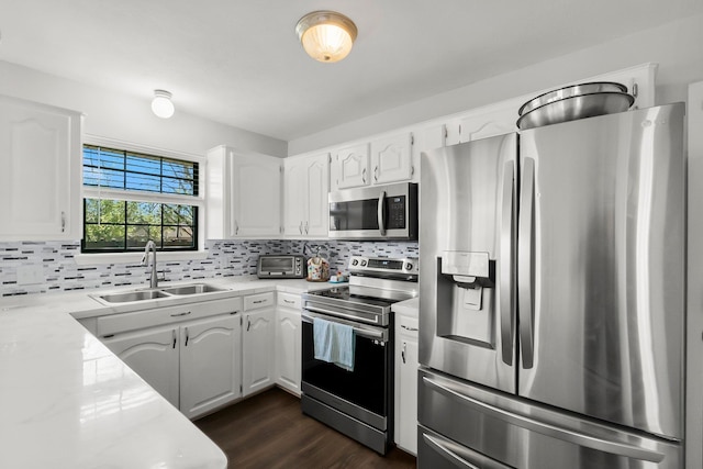 kitchen featuring a sink, tasteful backsplash, white cabinetry, stainless steel appliances, and light countertops