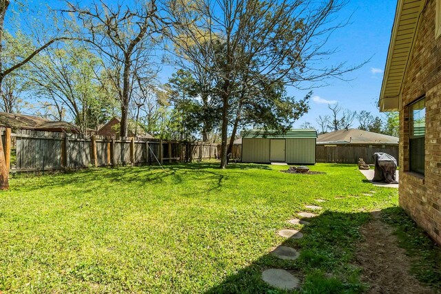 view of yard featuring a fenced backyard, an outdoor fire pit, an outdoor structure, and a shed