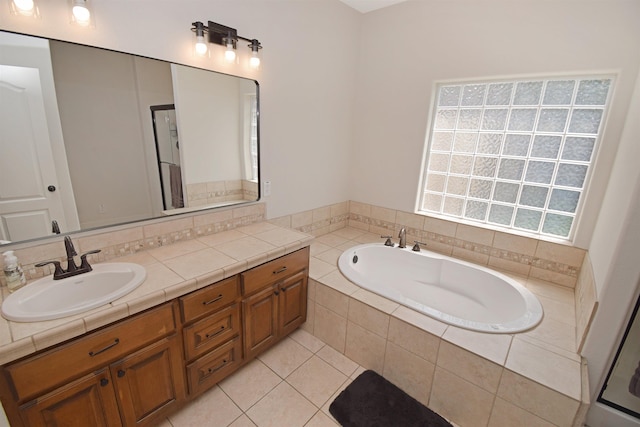 bathroom featuring tile patterned flooring, vanity, and tiled tub