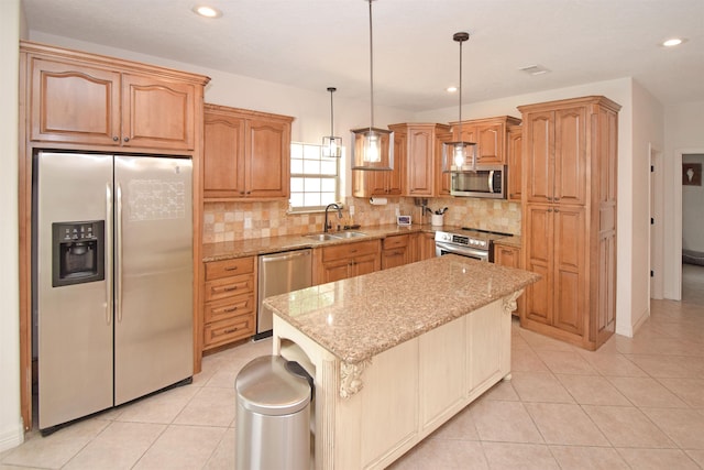 kitchen with appliances with stainless steel finishes, sink, hanging light fixtures, a center island, and light stone counters