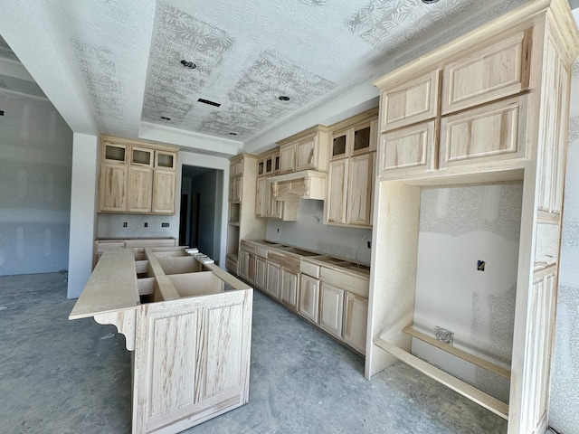 kitchen featuring light brown cabinets, a kitchen island, stovetop, and custom range hood