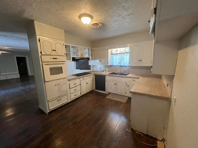 kitchen with dark hardwood / wood-style floors, a textured ceiling, black appliances, white cabinets, and sink