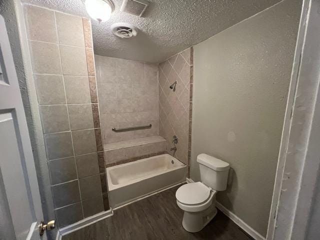 bathroom with toilet, tiled shower / bath combo, a textured ceiling, and hardwood / wood-style flooring