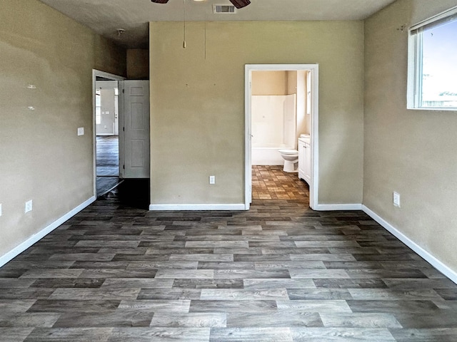 unfurnished bedroom featuring ensuite bathroom and dark wood-type flooring