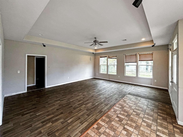 unfurnished living room featuring a raised ceiling, ceiling fan, and dark hardwood / wood-style flooring