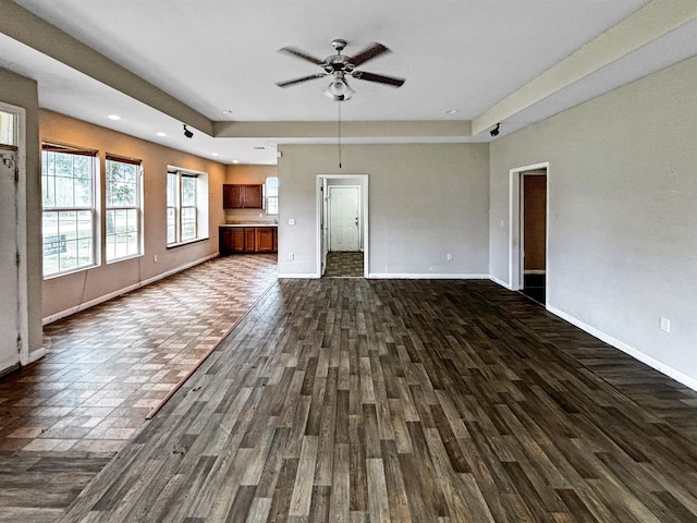 unfurnished living room with ceiling fan and dark wood-type flooring