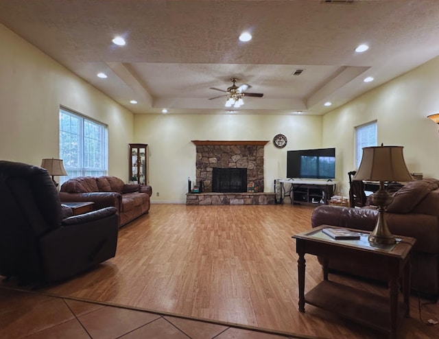 8135 Dawn Dr, Beaumont, TX 77705 - living room featuring a tray ceiling, ceiling fan, wood finished floors, a stone fireplace, and recessed lighting