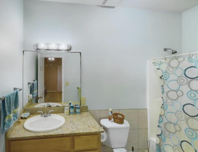 8135 Dawn Dr, Beaumont, TX 77705 - bathroom with toilet, a shower with shower curtain, vanity, and tile walls