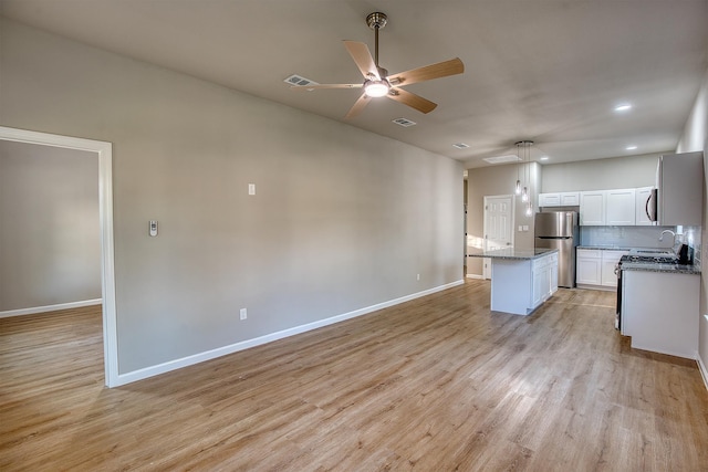 kitchen with a center island, appliances with stainless steel finishes, tasteful backsplash, light hardwood / wood-style floors, and white cabinetry