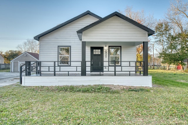 view of front of home with an outdoor structure, covered porch, a front yard, and a garage