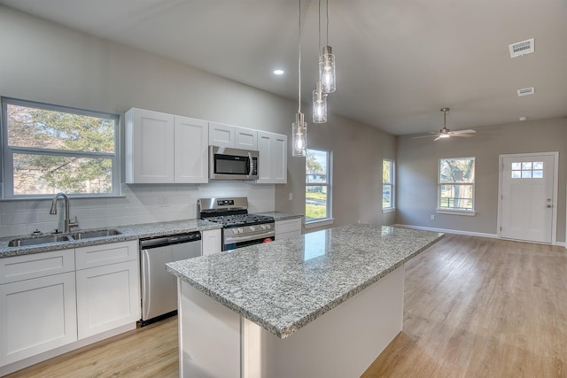 kitchen with ceiling fan, a center island, sink, white cabinets, and appliances with stainless steel finishes