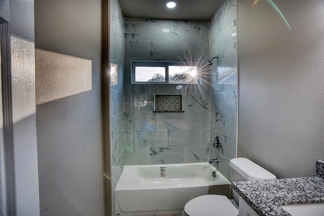 full bathroom featuring vanity, tiled shower / bath combo, and toilet