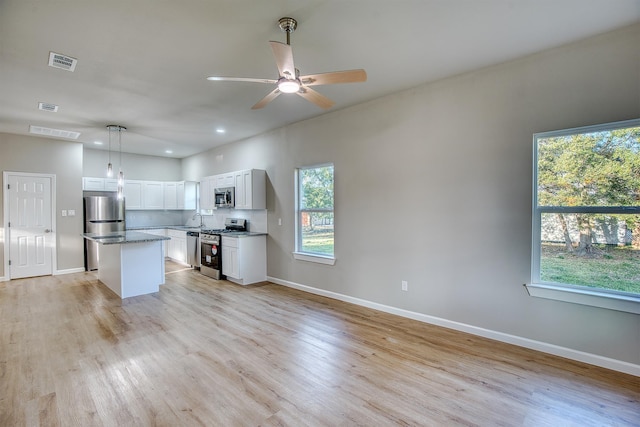 kitchen with white cabinetry, a center island, sink, stainless steel appliances, and decorative light fixtures