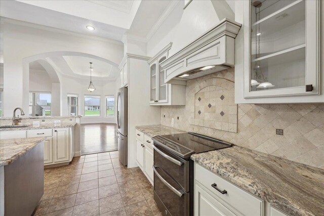 1215 Bourbon St, Bridge City, TX 77611 - kitchen featuring stainless steel appliances, crown molding, custom range hood, a sink, and light stone countertops