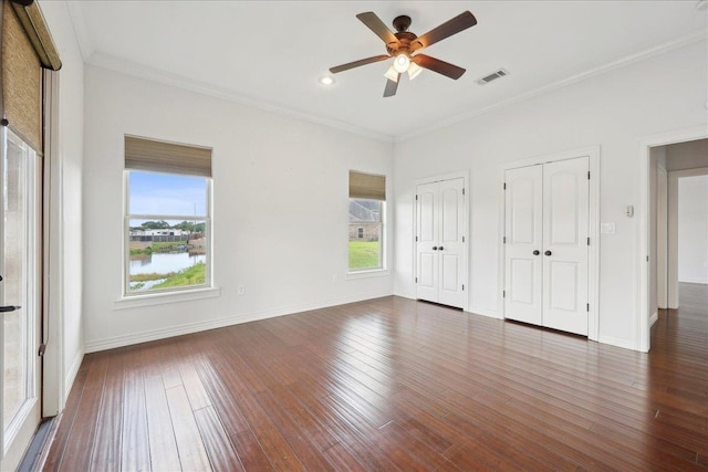 1215 Bourbon St, Bridge City, TX 77611 - unfurnished bedroom with multiple windows, two closets, dark wood-style flooring, ornamental molding, and recessed lighting