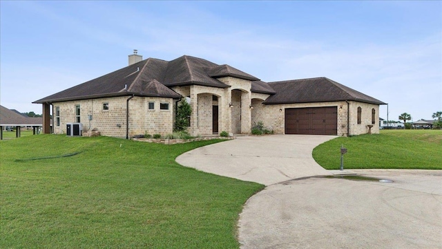 1215 Bourbon St, Bridge City, TX 77611 - french country style house featuring central air condition unit, brick siding, a front lawn, concrete driveway, and an attached garage