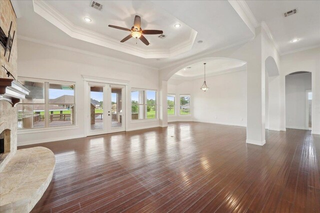 1215 Bourbon St, Bridge City, TX 77611 - unfurnished living room with arched walkways, a fireplace, a raised ceiling, a ceiling fan, and dark wood finished floors