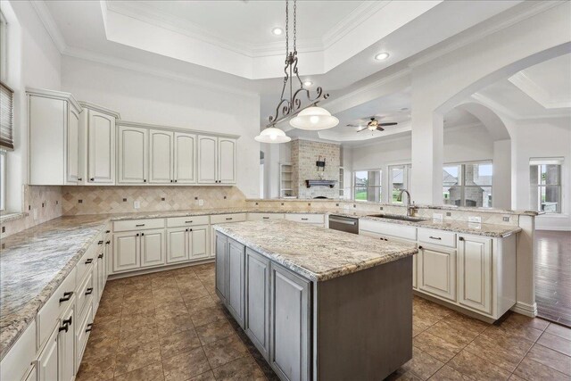 1215 Bourbon St, Bridge City, TX 77611 - kitchen featuring a raised ceiling, a sink, ceiling fan, a kitchen island, and stainless steel dishwasher