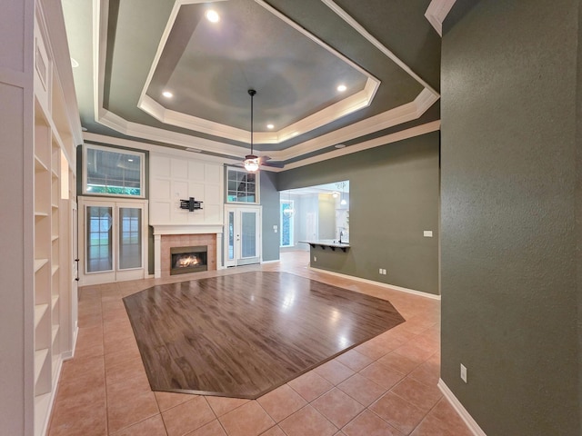 3760 Seminole Dr, Beaumont, TX 77707 - unfurnished living room featuring light tile patterned floors, a tray ceiling, a tiled fireplace, ceiling fan, and baseboards