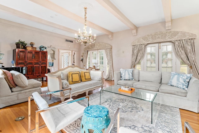 living room with beamed ceiling, wood-type flooring, and an inviting chandelier