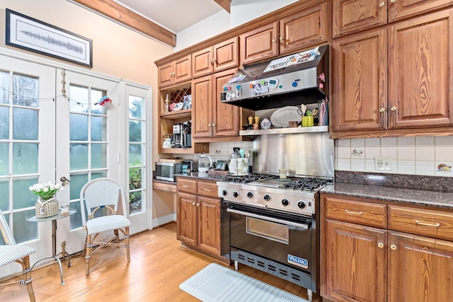 kitchen featuring dark stone counters, stainless steel appliances, tasteful backsplash, and light hardwood / wood-style floors