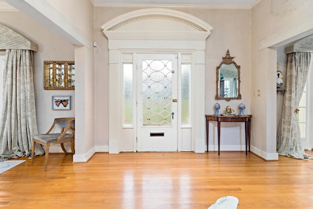 entryway with light wood-type flooring and ornamental molding