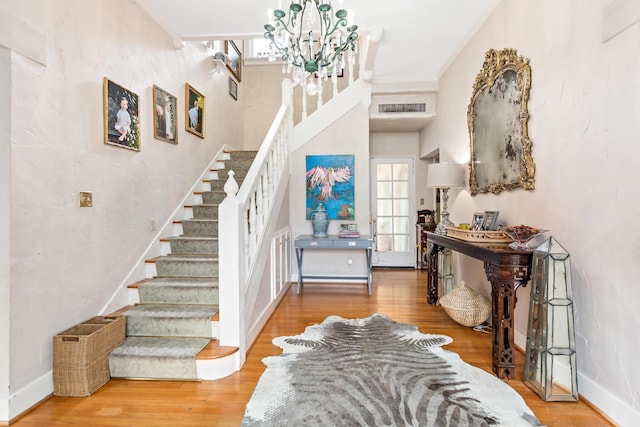 entrance foyer featuring wood-type flooring, crown molding, and a notable chandelier