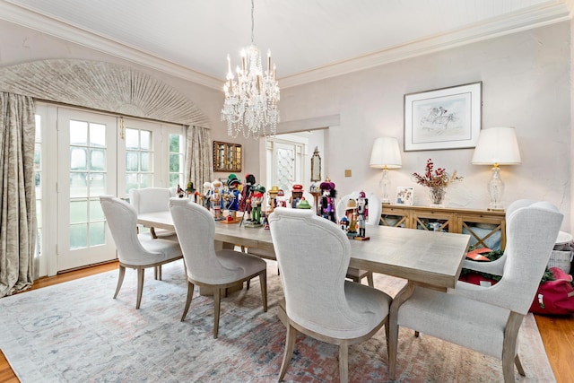 dining room with wood-type flooring, ornamental molding, and a chandelier