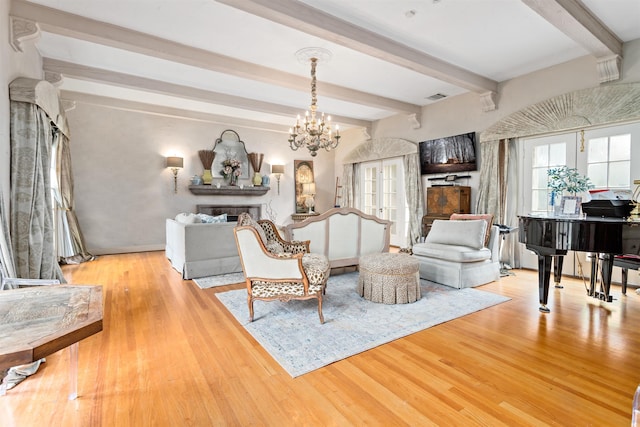 living room featuring beam ceiling, a chandelier, and light wood-type flooring