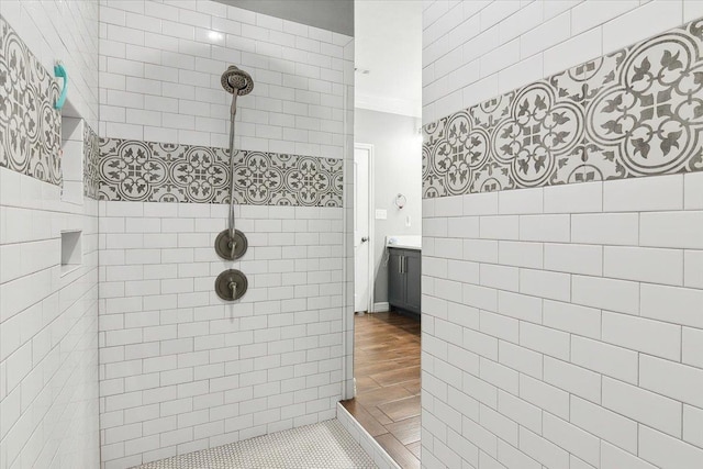 bathroom with vanity, tile patterned flooring, crown molding, and a tile shower