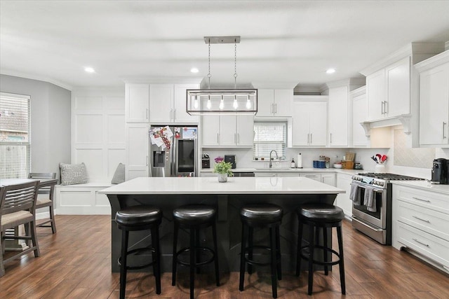 kitchen with appliances with stainless steel finishes, decorative light fixtures, sink, white cabinets, and a center island