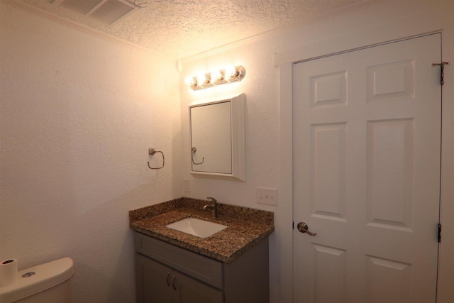 bathroom featuring crown molding, toilet, vanity, a textured ceiling, and a textured wall