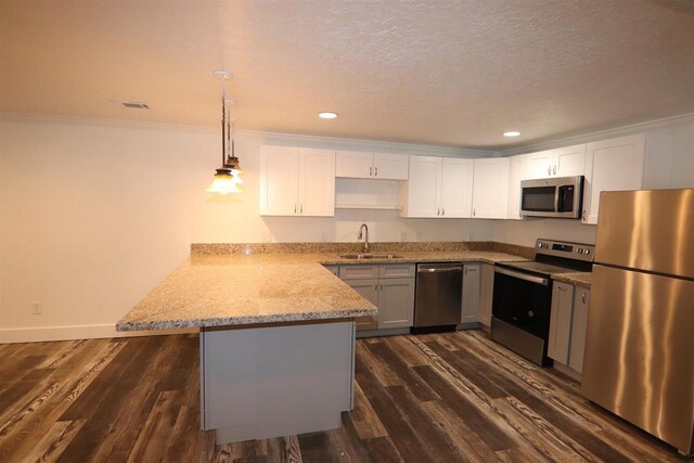 kitchen with a sink, appliances with stainless steel finishes, a peninsula, dark wood-style floors, and visible vents