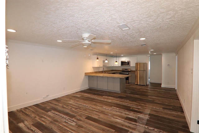 kitchen featuring dark wood finished floors, white cabinets, appliances with stainless steel finishes, and a peninsula