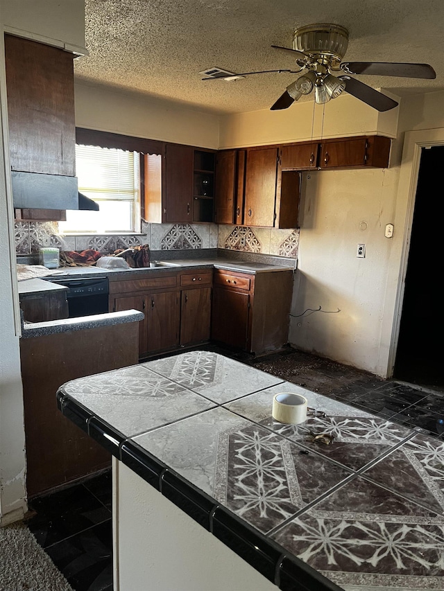 kitchen with sink, a textured ceiling, tile counters, black dishwasher, and decorative backsplash