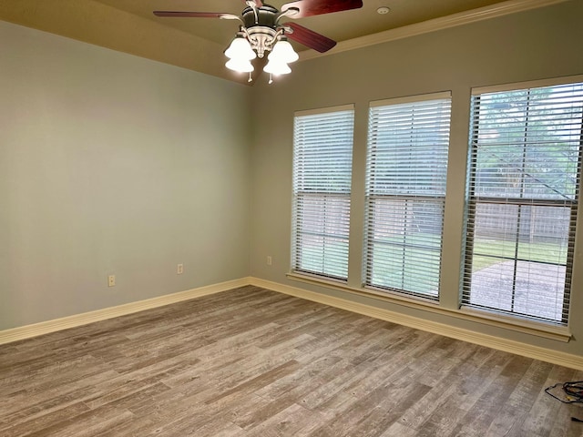 spare room featuring a ceiling fan, wood finished floors, baseboards, and ornamental molding