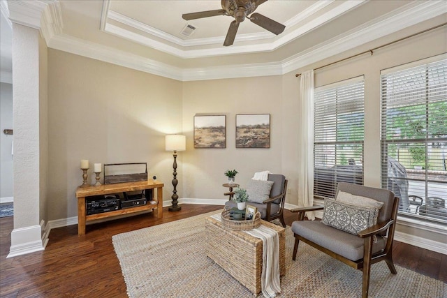 living area featuring dark wood-style flooring, ceiling fan, a raised ceiling, baseboards, and ornamental molding