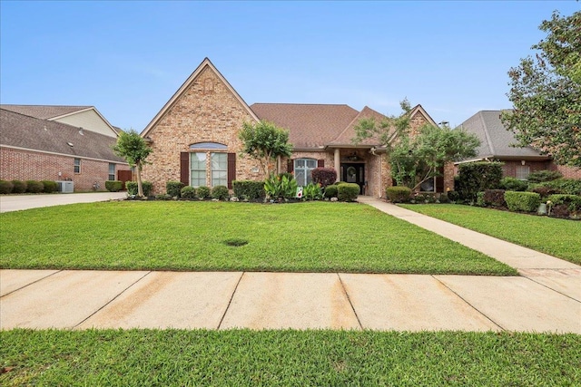 view of front facade with central air condition unit, a front lawn, and brick siding