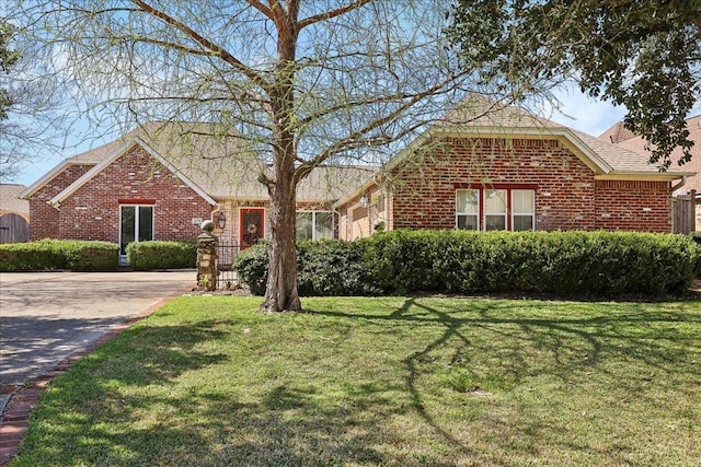 view of front facade with driveway, a front yard, and brick siding